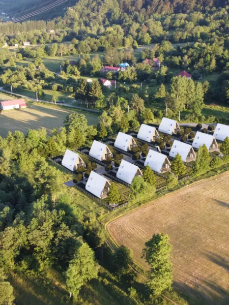 Aerial view of detached chalets near Kolašin Montenegro - surrounded by river, fields and coniferous forests